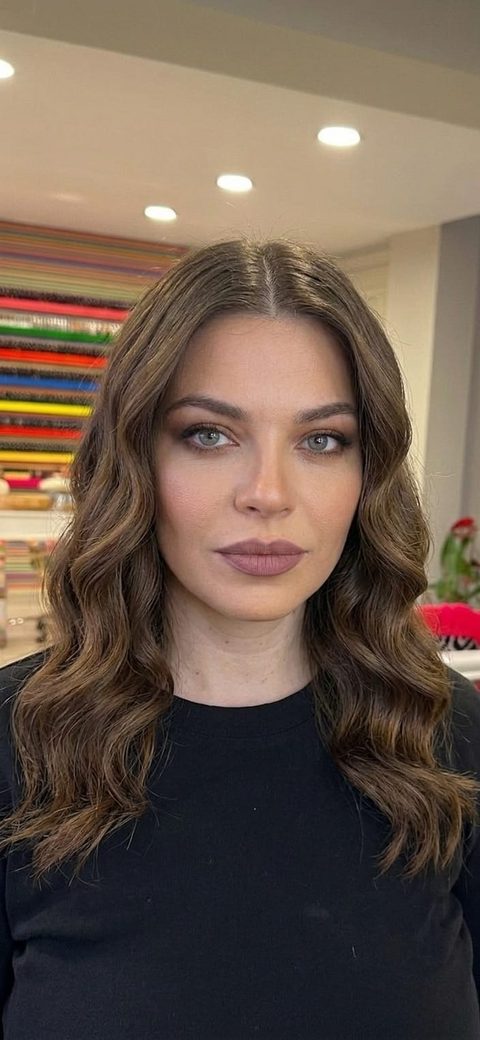 After: the same woman previewing a new wavy hairstyle generated by the AI hairstyle changer, face and features unchanged
